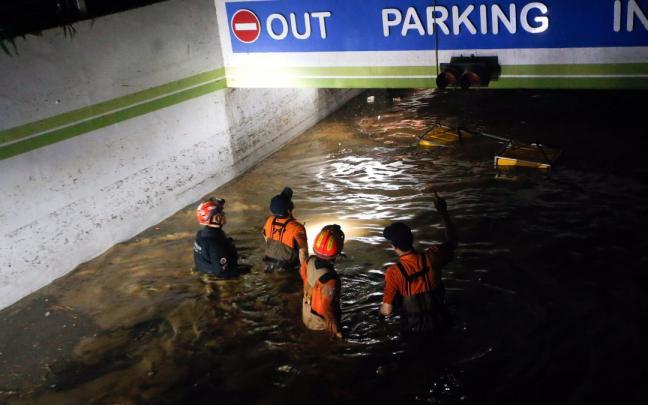 Los bomberos buscan supervivientes en el parking inundado.