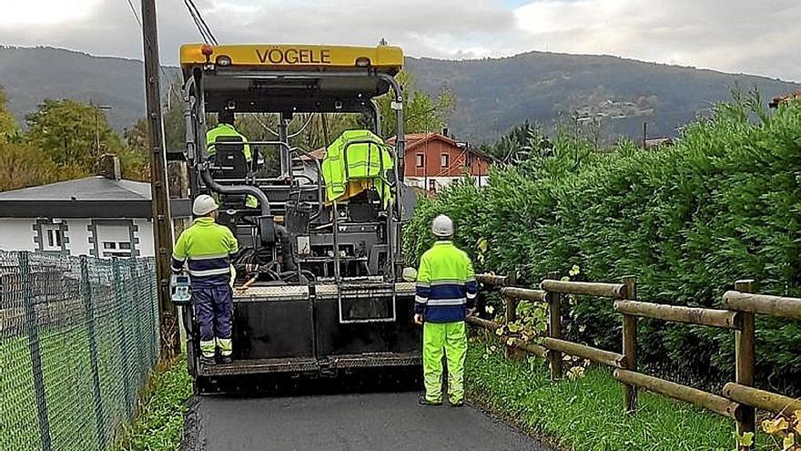 Operarios asfaltan un camino rural en Derio.