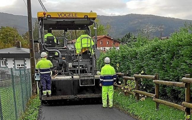 Operarios asfaltan un camino rural en Derio.