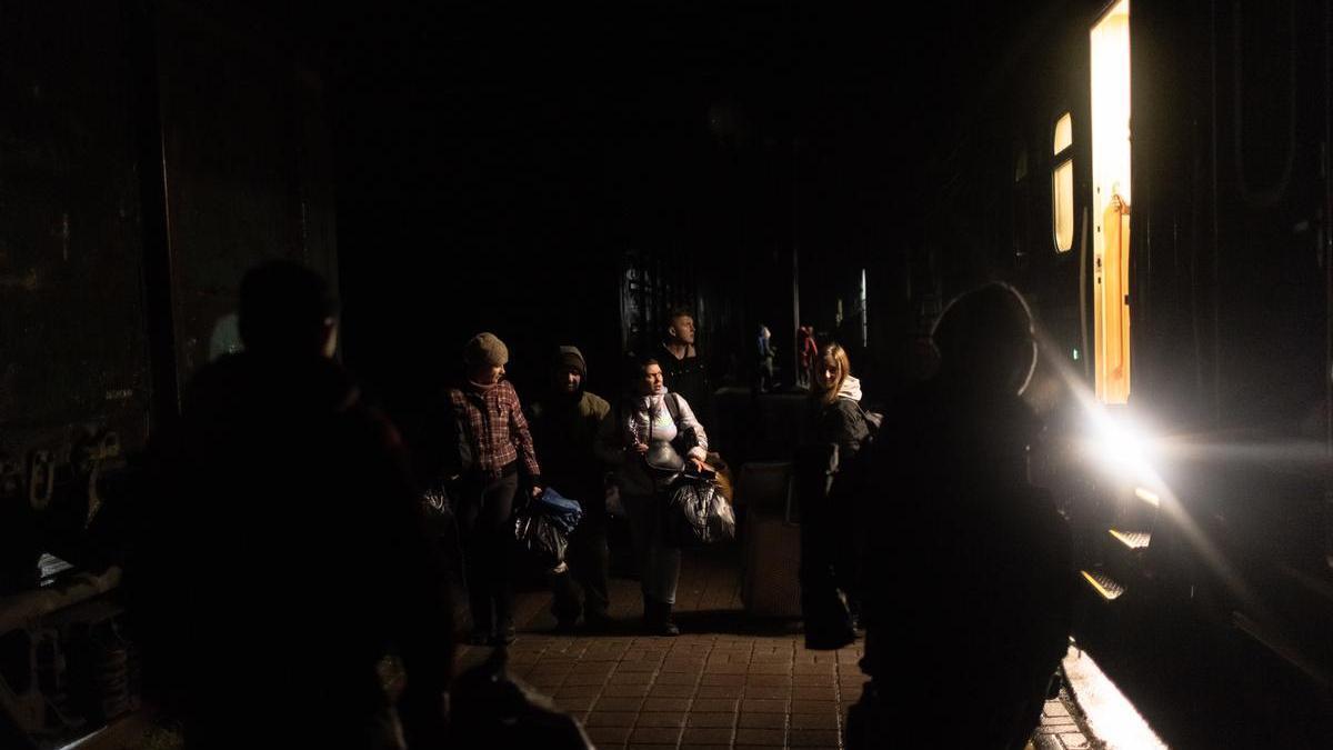 Varias personas son evacuadas de Jersón en la penumbra provocada por los bombardeos rusos.