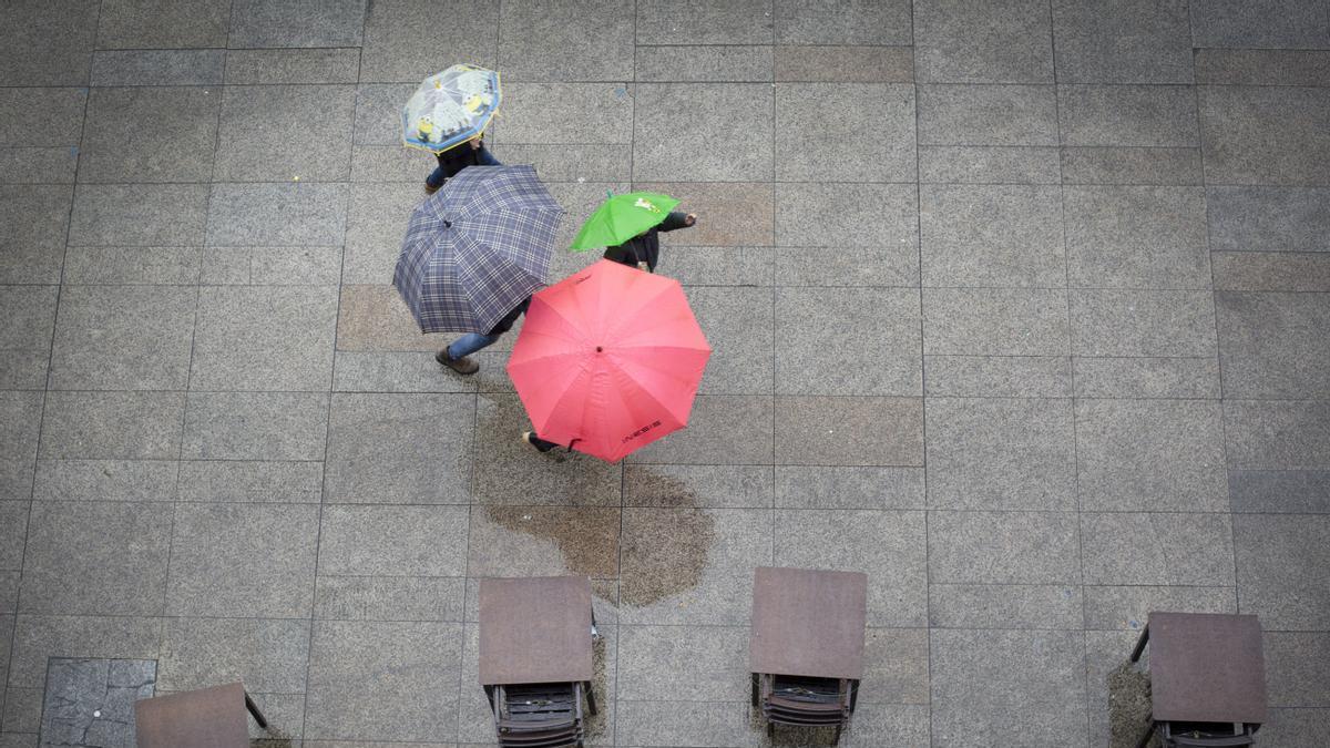 Varias personas se protegen de la lluvia con un paraguas este domingo en Pamplona.