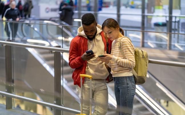 Una pareja de viajeros trata de conectarse a una red móvil con la que poder acceder a internet. Una pareja de viajeros trata de conectarse a una red móvil con la que poder acceder a internet.