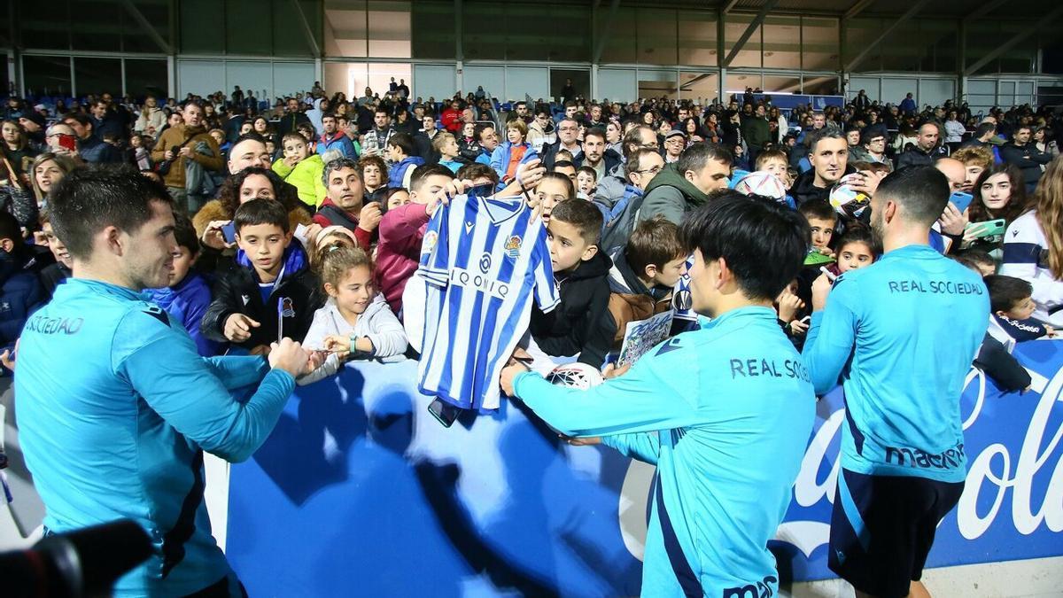 Futbolistas de la Real atienden a j&oacute;venes aficionados que les solicitan firmas y fotograf&iacute;as, este lunes en Zubieta.