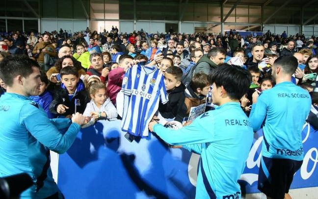 Futbolistas de la Real atienden a j&oacute;venes aficionados que les solicitan firmas y fotograf&iacute;as, este lunes en Zubieta.