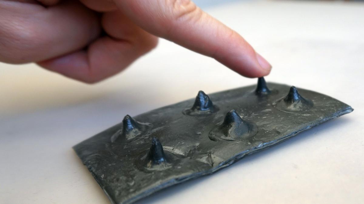 Hoja de material sobre la que se han creado bultos similares al formato braille.