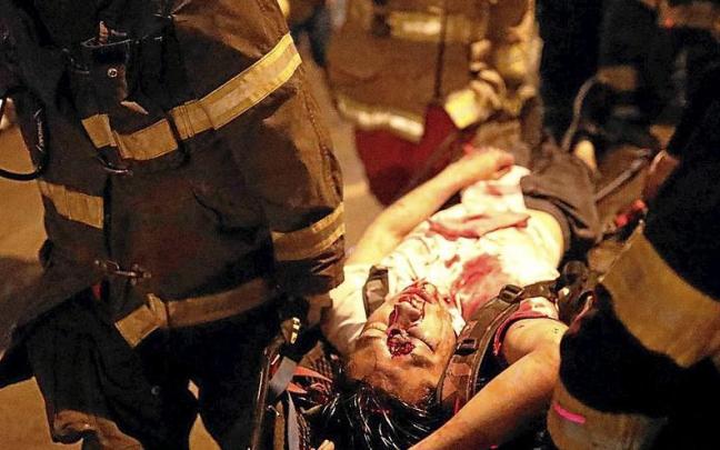 Un manifestante herido por el impacto de una bomba lacrim&oacute;gena es trasladado a una ambulancia. | FOTO: EFE