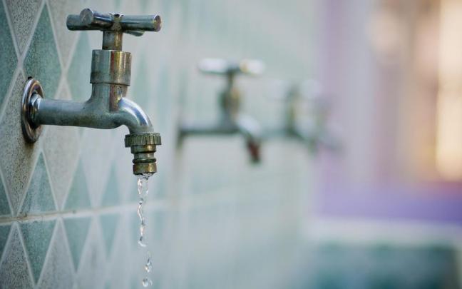 Un chorro de agua sale de un grifo a medio cerrar. Un chorro de agua sale de un grifo a medio cerrar.