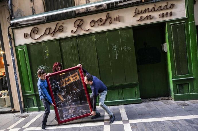 Dos empleados del Café Roch trasladan un cuadro del local, tras recoger las últimas pertenencias antes de que se ejecute el desahucio.