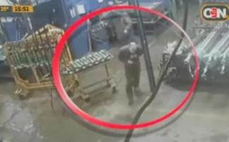 El empleado, en el círculo rojo, recién apuñalado con las manos en el pecho.