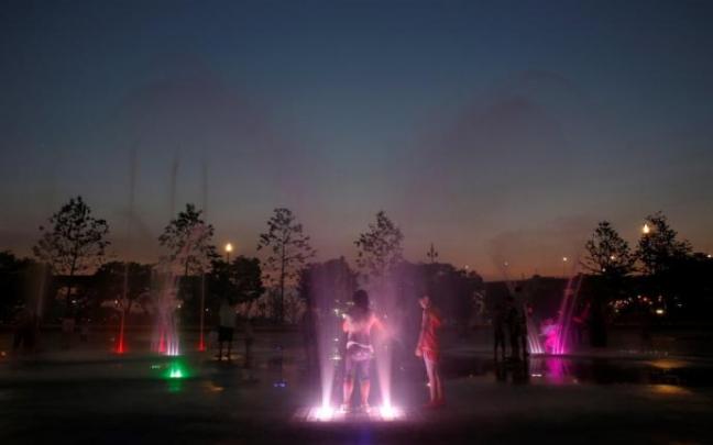 Dos jóvenes se refrescan en una fuente pública para aliviar el sofocante calor nocturno que sufren. Dos jóvenes se refrescan en una fuente pública para aliviar el sofocante calor nocturno que sufren.