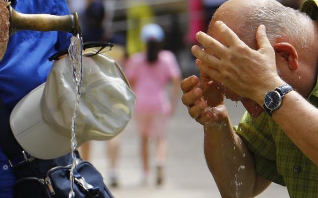 Un hombre se refresca en una fuente. Un hombre se refresca en una fuente.