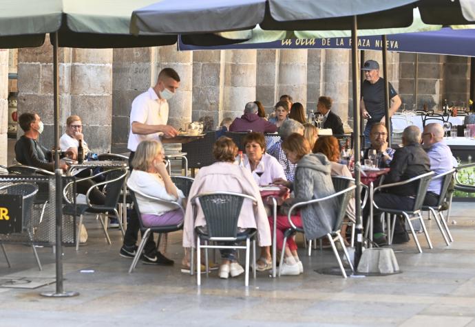 Un camarero sin relación con la información sirviendo mesas en una terraza.