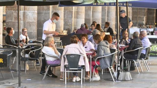 Un camarero sin relación con la información sirviendo mesas en una terraza.