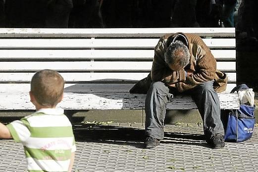 Un niño observa a una persona sin hogar.
