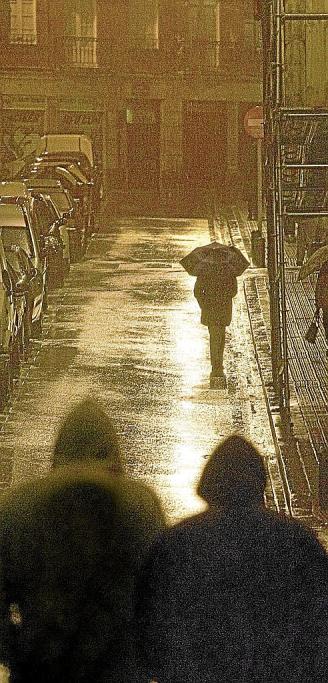 Dos jóvenes caminan por una calle de Bilbao en una noche lluviosa. Foto: Zigor Alkorta