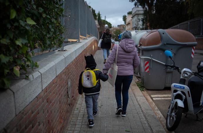 Una mujer lleva a un niño al colegio en Barcelona.