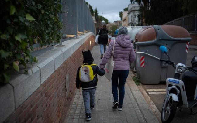 Una mujer lleva a un niño al colegio en Barcelona.
