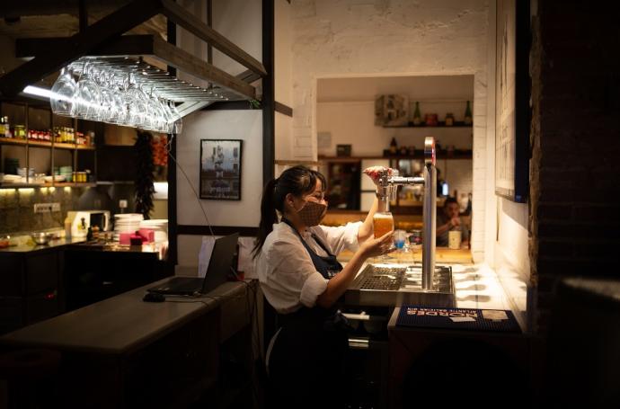 Una camarera sirve una cerveza en el interior de un bar en Barcelona.