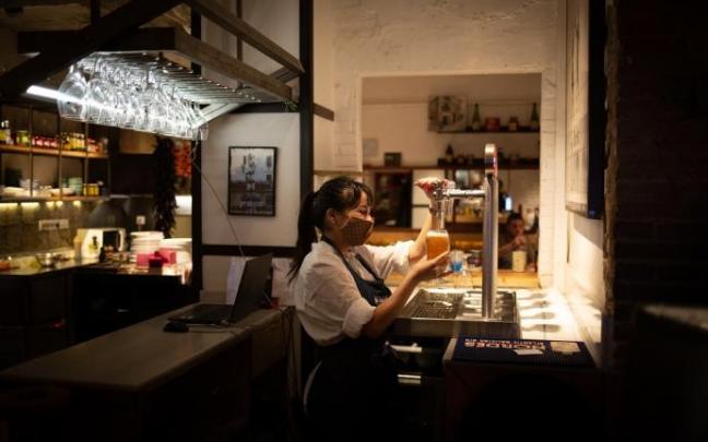 Una camarera sirve una cerveza en el interior de un bar en Barcelona. Una camarera sirve una cerveza en el interior de un bar en Barcelona.