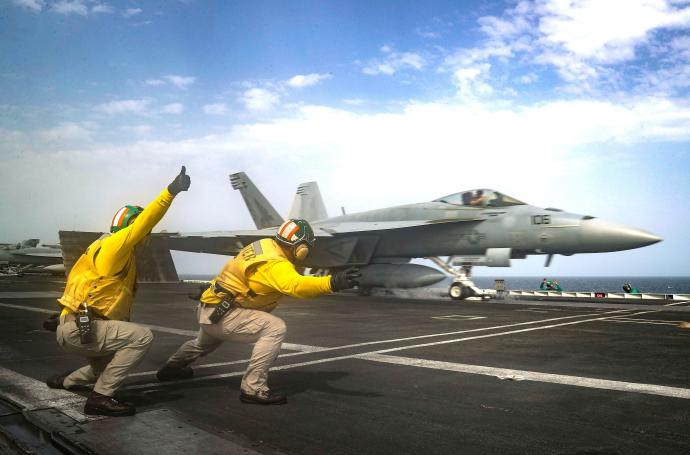 Dos marines dan el visto bueno al despegue de un caza en la pista del portaaviones de clase Nimitz Abraham Lincoln.