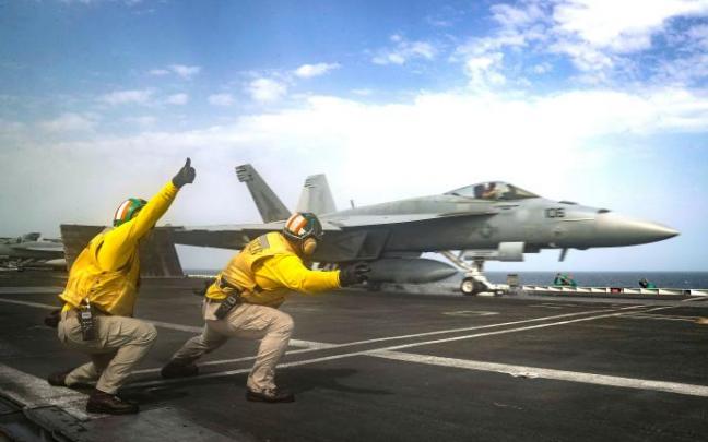 Dos marines dan el visto bueno al despegue de un caza en la pista del portaaviones de clase Nimitz Abraham Lincoln.