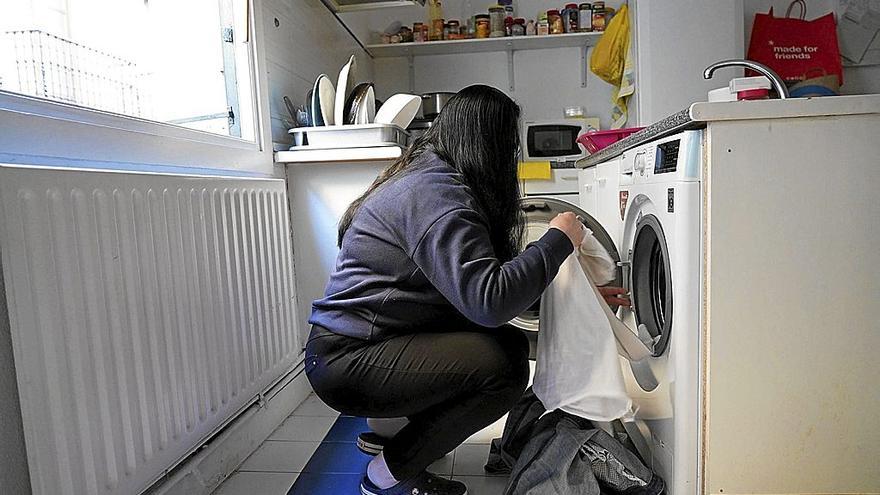 Una mujer con pobreza energética prepara una lavadora. | FOTO: PABLO VIÑAS