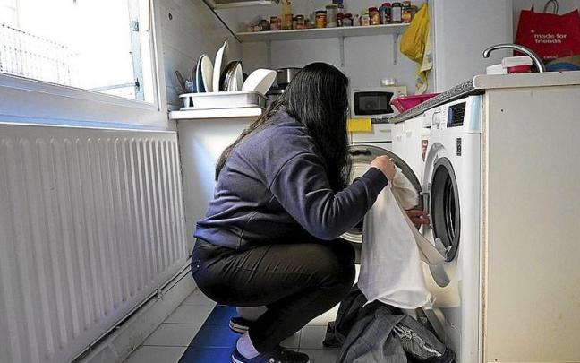 Una mujer con pobreza energética prepara una lavadora. | FOTO: PABLO VIÑAS