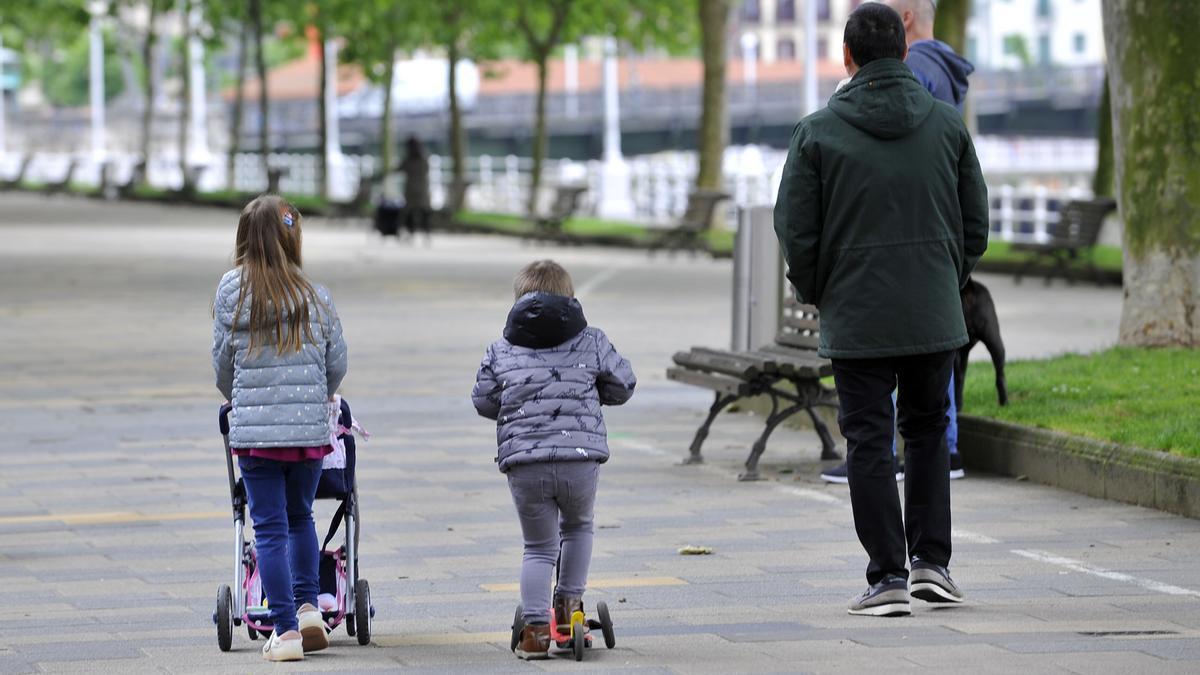 Un aita pasea con dos de sus hijos por el parque de Doña Casilda en Bilbao.