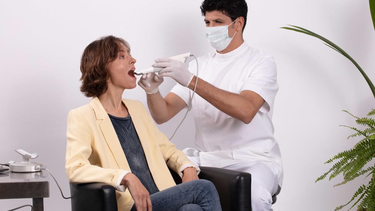 Una dentista pasa consulta a una mujer.
