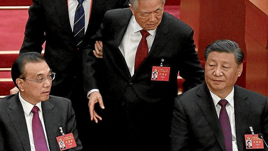 El expresidente Hu Jintao (centro) trata de hablar con Xi Jinping (derecha) que se muestra impasible.