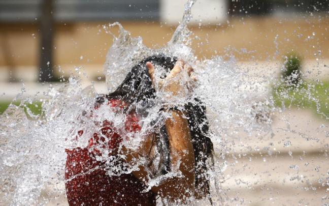 Una niña juega en una fuente para aliviar las altas temperaturas. Una niña juega en una fuente para aliviar las altas temperaturas.