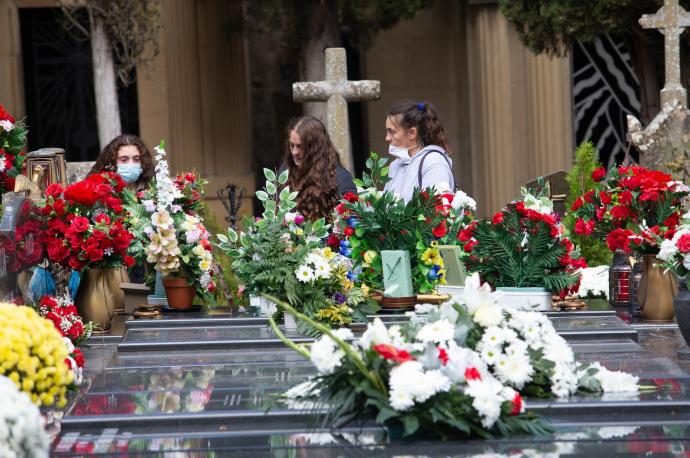 Visitantes depositando flores en el cementerio