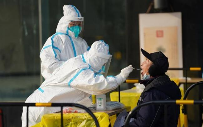 Sanitarios realizan a un hombre una prueba PCR en China.