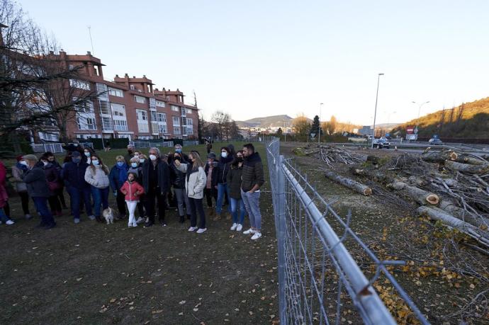 Un grupo de vecinos posa para la foto junto a las vallas que delimitan las obras del desdoble de la PA-30, para las que se han talado más de 100 chopos.