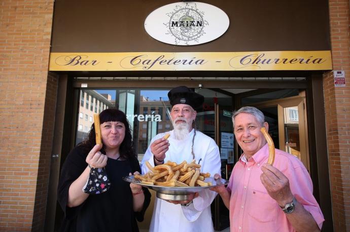 La cocinera Feli Martínez, en nuevo churrero Alberto Otel y el veterano que le enseñó el oficio, Miguel Alonso, con una buena bandeja de churros a las puertas deL Maian, en Ansoáin.