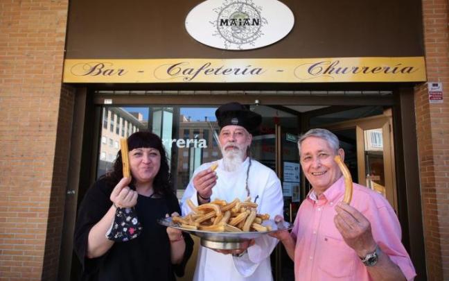 La cocinera Feli Martínez, en nuevo churrero Alberto Otel y el veterano que le enseñó el oficio, Miguel Alonso, con una buena bandeja de churros a las puertas deL Maian, en Ansoáin.