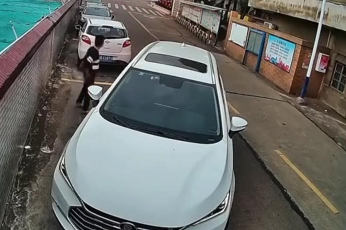 El conductor, al lado del coche tras ser incapaz de aparcarlo.
