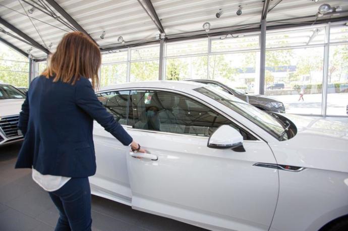 Una mujer abre un vehículo en un concesionario