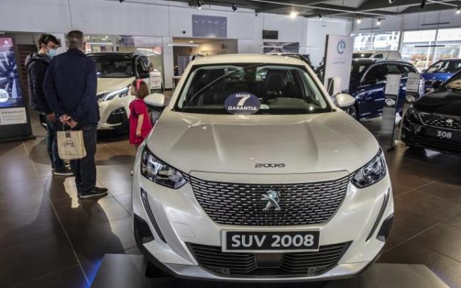 Dos personas contemplan un automóvil en un concesionario.