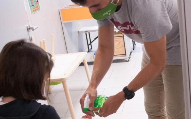 Un profesor echando gel en la maño de una escolar. Un profesor echando gel en la maño de una escolar.
