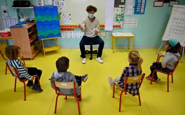 Una profesora con mascarilla da clases a un grupo reducido de alumnos en el colegio Champ l'Eveque.