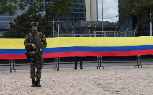 Un militar delante de una bandera de Colombia. Un militar delante de una bandera de Colombia.