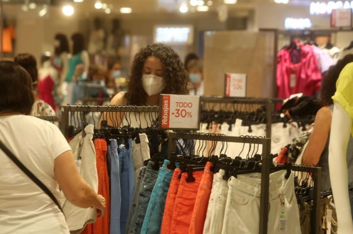 Dos mujeres miran las prendas en una tienda de ropa.