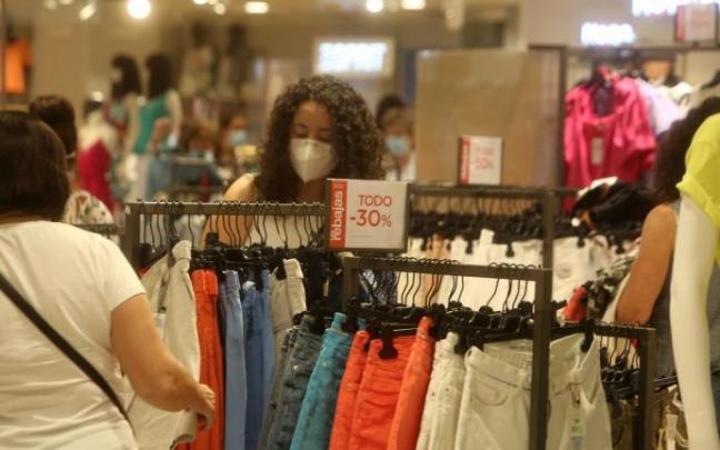 Dos mujeres miran las prendas en una tienda de ropa.