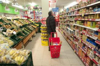 Un hombre observa la estantería repleta de alimentos de un supermercado.