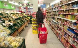 Un hombre observa la estantería repleta de alimentos de un supermercado.