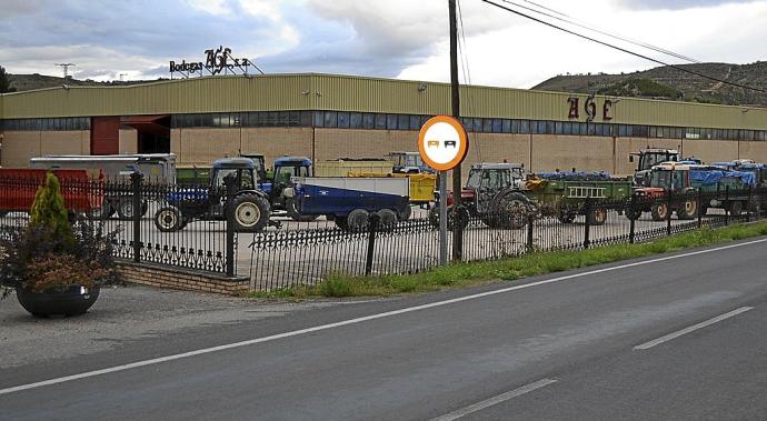 Una fila de tractores espera a la entrada de una bodega para descargar las uvas de sus remolques.