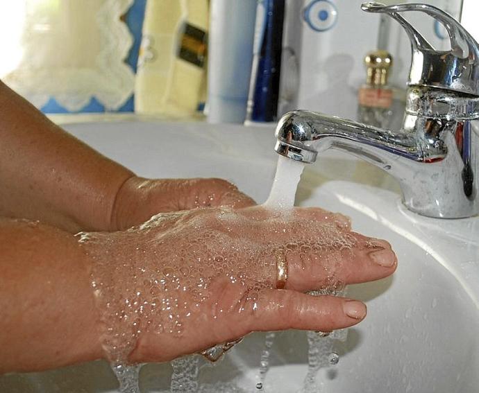 Una mujer se lava las manos en un lavabo.