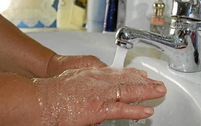 Una mujer se lava las manos en un lavabo.