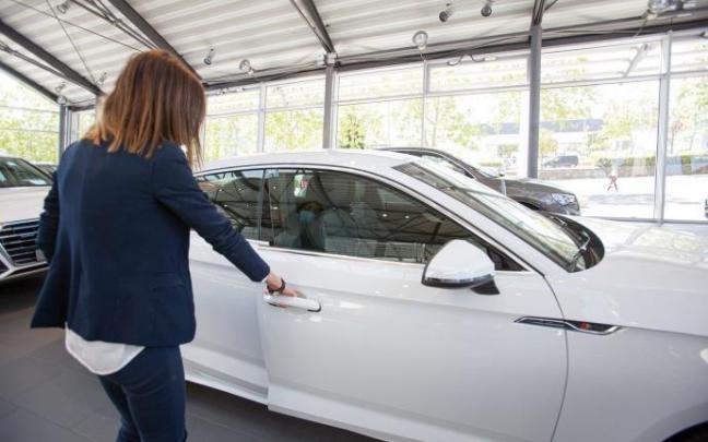 Una mujer mira un coche en un concesionario.
